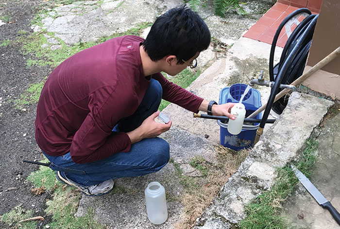 Student Kevin Zhu collects a water sample from a community member's home in Villalba.