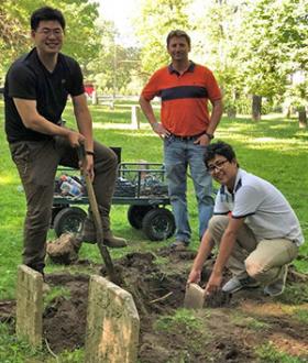 Ph.D. student Siqi Wang, ICT engineer Michael Johnson, and Ph.D. student Shan Zhao unearth a buried gravestone. 