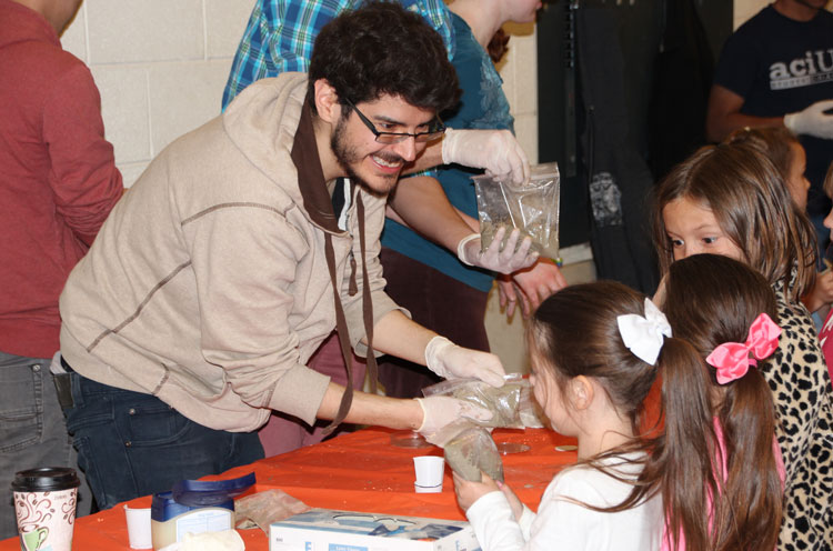 Robbie Damiani helps visiting students mix concrete to make souvenir coasters.