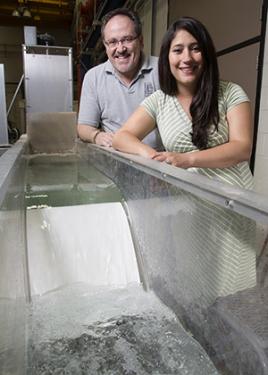 Marcelo Garcia and Tatiana Garcia pose by a physical model of a low head dam in the Ven T. Chow Hydrosystems Laboratory that represents Asian carp spawning location. 