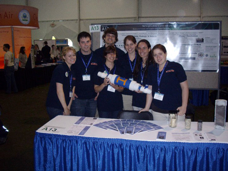 The group poses in front of their poster at the Expo.