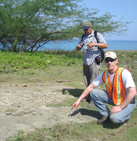 Professor Scott Olson examines a sand volcano created by liquefaction near the coast.
