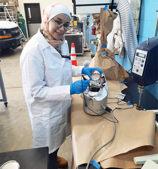 Yusra Alhadidi, CEE doctoral student, adds granulated plastics to asphalt bitumen before blending them with a high shear mixer at ATREL in Rantoul, Ill. earlier in June.
