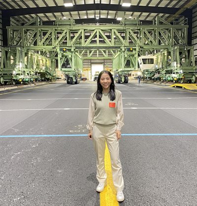 Qingwen Zhou, a University of Illinois Urbana-Champaign Department of Civil and Environmental Engineering doctoral candidate, poses in front of the National Airport Pavement Test Vehicle, a rail-based device capable of simulating aircraft weighing up to 1.3 million pounds, at Federal Aviation Administration&amp;amp;amp;rsquo;s National Airport Pavement Test Facility.