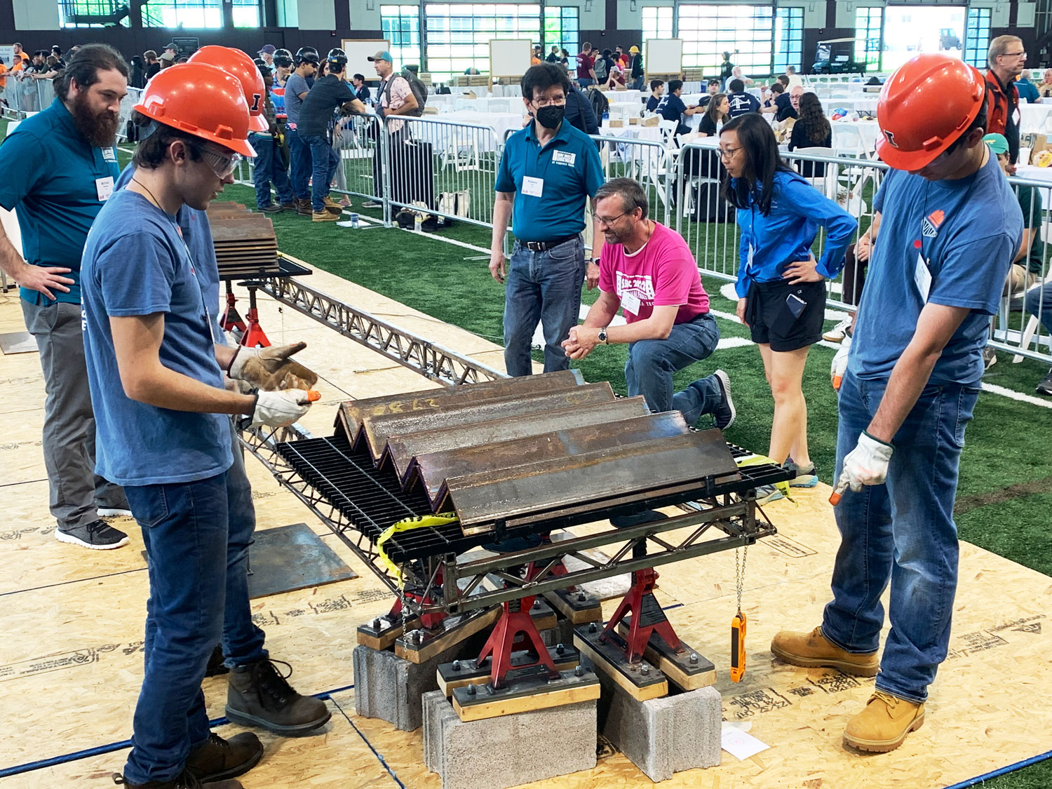 The UIUC Student Steel Bridge Team load-tests their bridge at the national SSBC under the watchful eyes of AISC Director of Education Christina Harber (BS 02) and Virginia Tech Prof. Matt Eatherton (PhD 2010, kneeling).