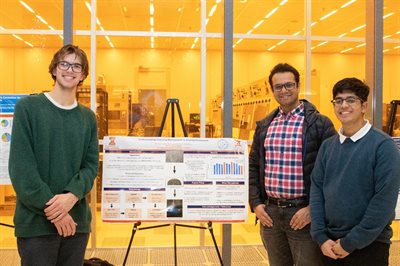 UIUC students Colin Macleod (left) and Rohit Choudhary (right) smile in front of their research poster with mentor Akash Bajaj, a Department of Civil and Environmental Engineering doctoral candidate.