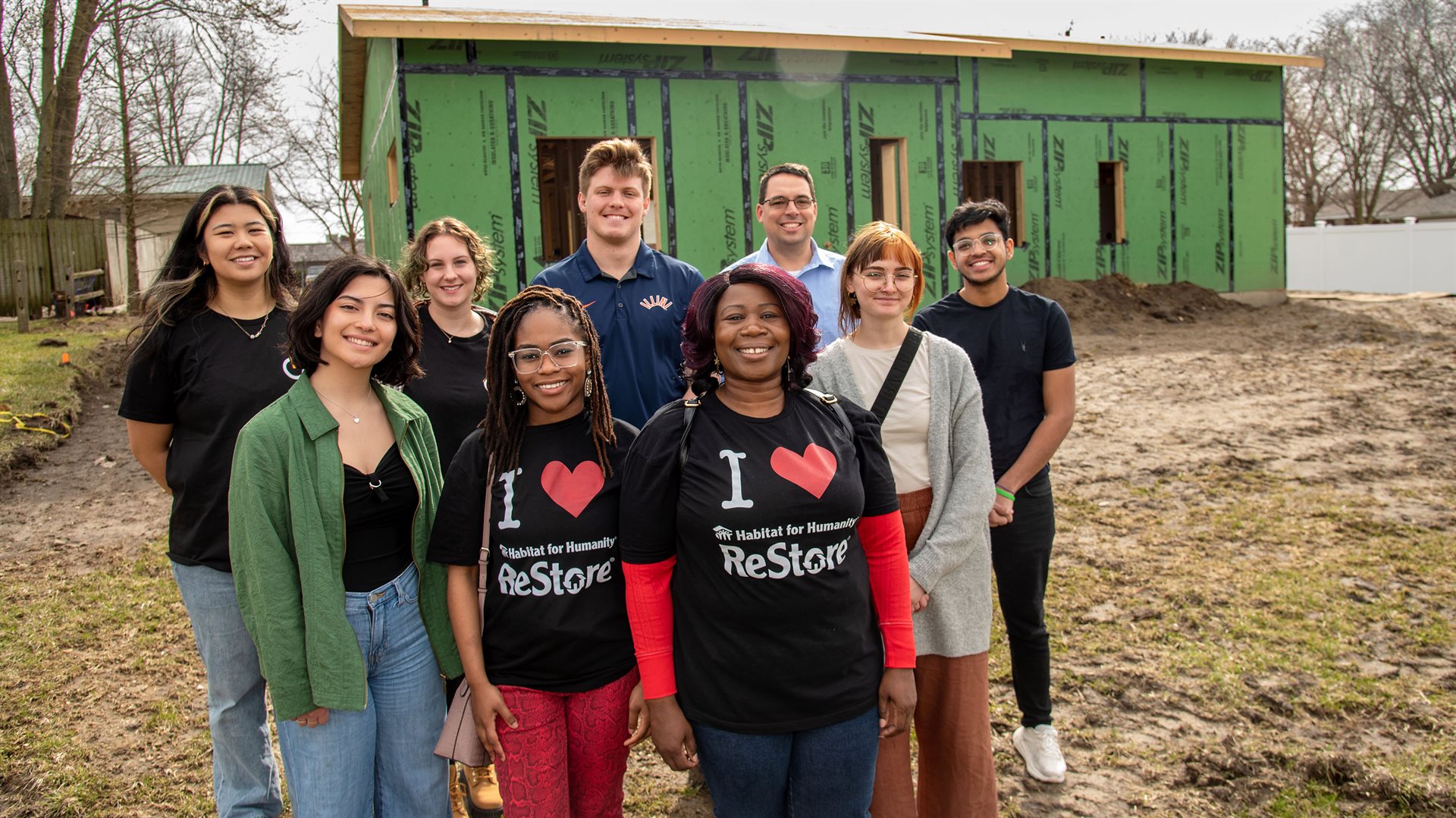 Halie Collins, foreground left, joins fellow Student members of Illinois Solar Decathlon and Elonda Elston, foreground right, and her daughter, Monae Latchison, center, for a group photo in front of their future home at the RENU Home/Habitat for Humanity site in Rantoul. Habitat Executive Director Chad Hoffman is pictured back row, second from right.