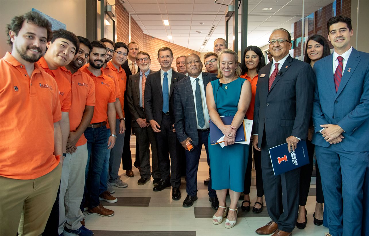 Transportation engineering students and faculty pose at the entrance to the Kavita and Lalit Bahl Smart Bridge with (center) Pete Buttigieg, Secretary of the U.S. Department of Transportation; Illinois Department of Transportation Omer Osman; U.S. Representative Nikki Budzinski; Dean of The Grainger College of Engineering Rashid Bashir.