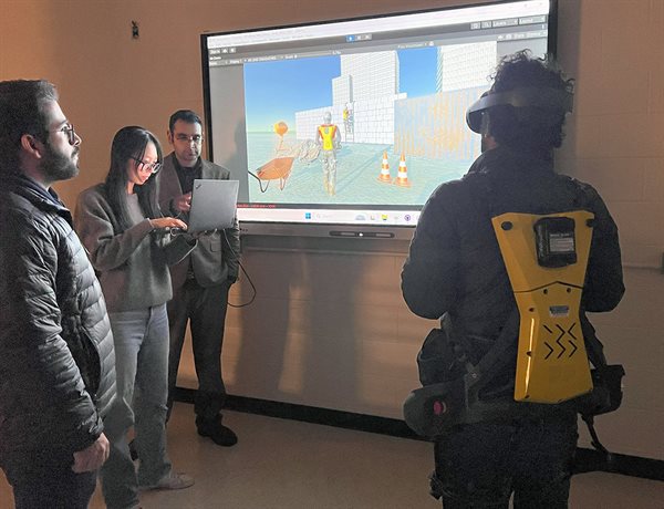 Houtan Jebelli, along with doctoral students Shayan Shayesteh and Yuming Zhang, observes a trainee interacting with a construction robot in the early prototype of the human-centric VR training environment.